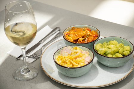 Téléchargez les photos : Assortiment avec différents plats de pâtes et verre de vin blanc gnocchi pesto tagliatelle et ravioli - en image libre de droit