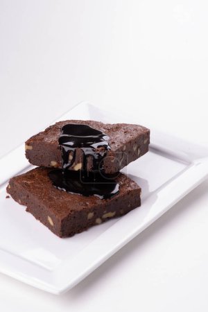 two pieces of chocolate brownie with organic nuts and chocolate icing