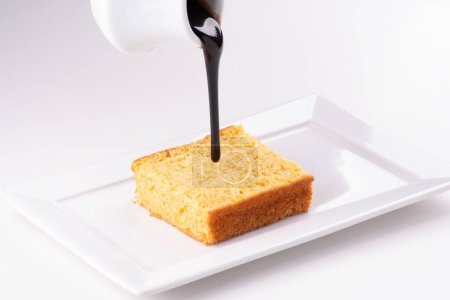 assiette blanche avec la main de gâteau de carotte versant soigneusement des gouttes de garniture de chocolat en gros plan