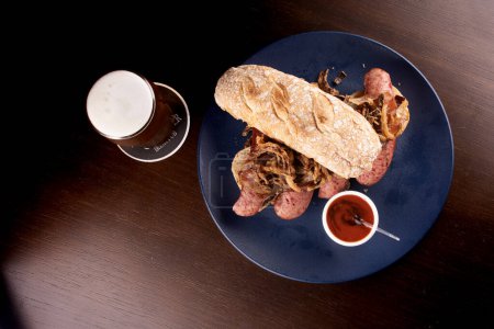 sandwich à la saucisse de bock avec baguette d'oignon croustillante et sauce au poivre jumelée à de la bière artisanale ale ale ipa apa vue de dessus