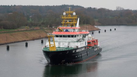 Foto de Kiel Canal, Alemania - 11 24 2022: Buque de investigación con pabellón alemán en marcha en el canal de navegación alemán mientras el clima es malhumorado - Imagen libre de derechos