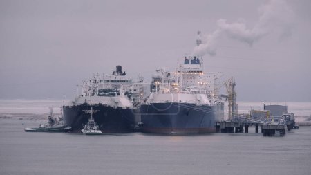 Foto de Unidad flotante de almacenamiento y regasificación y transportista de gas natural licuado en el puerto durante las operaciones de buque a buque - Imagen libre de derechos
