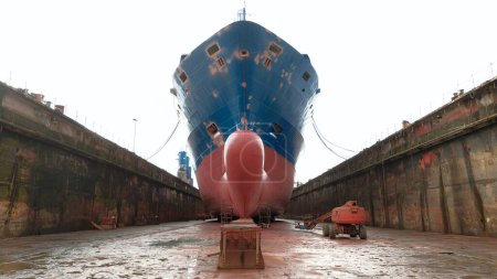 Emden, Germany - 02 20 2023: Front view of the container vessel in the shipyard during dry-docking and repairs. Bow of the vessel from the bottom of the shipyard.