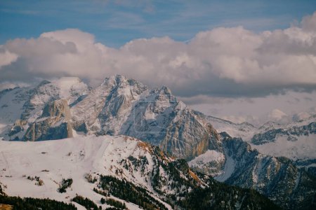 Téléchargez les photos : Une chaîne de montagnes rocheuses entourée de forêts alpines avec des sommets enneigés en arrière-plan - en image libre de droit