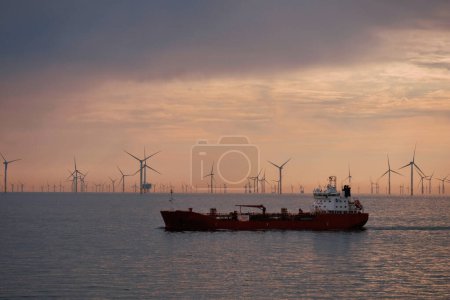 Téléchargez les photos : Citerne pratique en cours par temps calme dans la mer du Nord avec un parc d'éoliennes en arrière-plan. Production d'énergie durable en mer. Technologie de production éolienne offshore - en image libre de droit