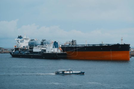 Floating storage and regasification unit. Liquified natural gas bunkering vessel and oil tanker powered by LNG in the port during the ship-to-ship operations.