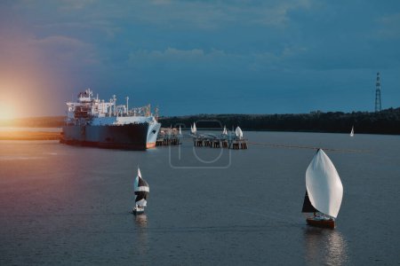 Téléchargez les photos : FSRU en Lituanie. Unité flottante de regazéification du stockage de GNL. Citerne de GNL dans le port européen avec plusieurs voiliers naviguant autour. Concept de solutions de GNL flottant. Énergie future - en image libre de droit