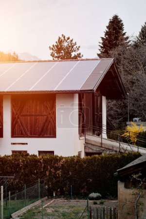 Téléchargez les photos : Maison avec panneaux solaires sur le toit. Énergie produite par la nature. Énergie produite par le soleil. Systèmes photovoltaïques sur la maison privée dans la campagne. Technologie des semi-conducteurs. Réduction de l'empreinte carbone - en image libre de droit