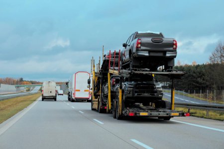 Car carrier trailer truck with brand new SUV cars for sale. New car delivery and shipping. Car transporter trailer loaded with many new cars for the customers. Two-level modular hydraulic semi-trailer