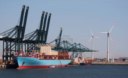 Téléchargez les photos : Grand porte-conteneurs dans le port avec des éoliennes en arrière-plan - en image libre de droit