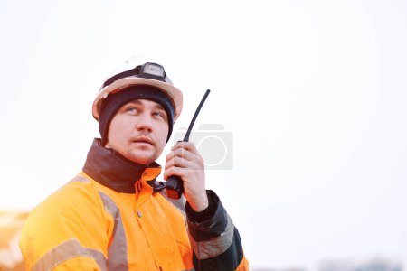 An Offshore Foreman With A Portable Radio Station In The Hand. Seafarer Communicating Using A VHF Radio Station. Communication At Sea During Distress. Project Manager Supervising The Ongoing Loading.