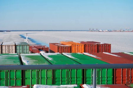Containerschiff segelt auf der gefrorenen International Shipping Fairway Route. Wasseroberfläche mit Eis bedeckt. Winterschifffahrt in der arktischen Region