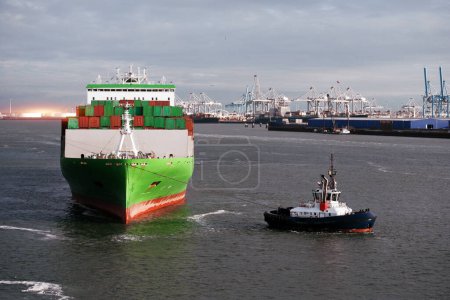 Téléchargez les photos : Aide au remorqueur pendant l'amarrage du grand navire porte-conteneurs dans le port - en image libre de droit