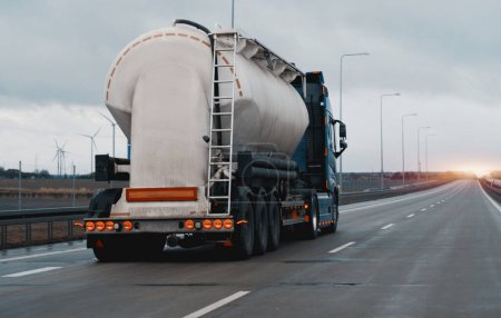 Petrol truck on highway hauling fossil oil refinery products. Fuel delivery transportation. Aviation fuel transportation. Compressed gas carrier truck rear view on a highway. Dairy products carrier
