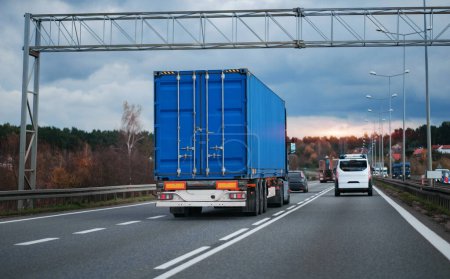 Photo for Blue semi-trailer trucks on the highway driving in the left traffic lane. Commercial vehicle for shipping and post delivery. Shipping of the goods on land door-to-door - Royalty Free Image