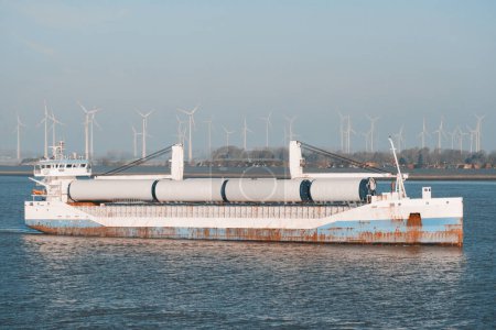 Wind Monopile Foundation Transportation. Stückgutschiff mit Windpark-Bauteilen auf Wetterdeck auf Lukendeckel aufgespült