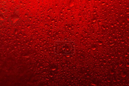 Foto de La textura de una gota de agua sobre un fondo rojo. - Imagen libre de derechos