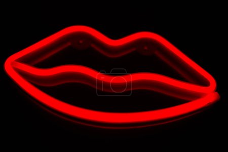 Verschwommene neonrote Lippen in Großaufnahme auf schwarzem Hintergrund.
