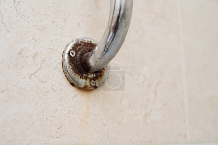 Rusty handle in the bathroom against the background of tiles. Moisture rust.