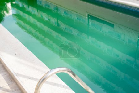 Schwimmbad mit schmutziggrünem Wasser in Nahaufnahme.