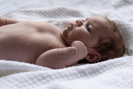 Foto de Una niña de un mes en una sábana blanca. Filmado a la luz del día. - Imagen libre de derechos