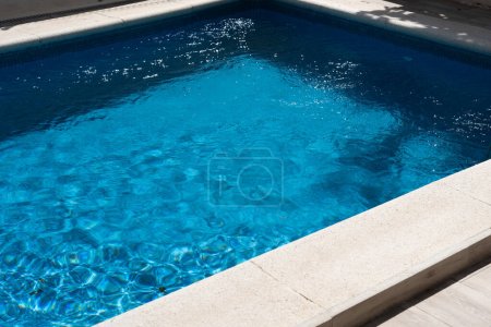 Wasserdichte Tasche mit Geld und Smartphone auf dem Hintergrund des Pools an einem sonnigen Sommertag.