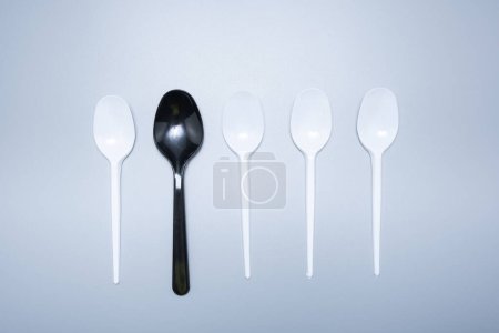 Foto de Cucharas de tenedores de plástico dispersas sobre un fondo gris. - Imagen libre de derechos