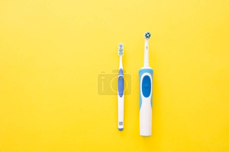 Téléchargez les photos : Brosse à dents électrique et analogique en bleu sur fond jaune. - en image libre de droit
