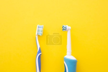 Téléchargez les photos : Brosse à dents électrique sur fond jaune. Ancien et nouveau compte dentaire. - en image libre de droit