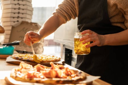 Téléchargez les photos : Gros plan d'un homme et d'une femme mains préparent une pizza dans la cuisine d'un restaurant, étalent la viande et huilent. par une journée ensoleillée, en contre-jour. Photo de haute qualité - en image libre de droit