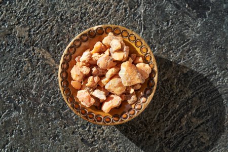 Photo for Styrax benzoin resin in a wooden bowl. Ingredient for essential oils. - Royalty Free Image
