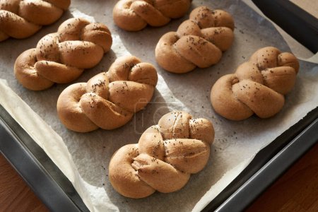 Téléchargez les photos : Rouleaux ou petits pains tressés frais à base de farine d'épeautre à grains entiers, sur une plaque à pâtisserie - en image libre de droit