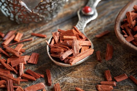 Téléchargez les photos : Copeaux de bois de santal rouge sur une cuillère en métal. Ingrédient pour huiles essentielles. - en image libre de droit