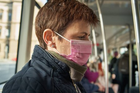 Photo for Woman wearing a pink coronavirus face mask in a tram due to COVID-19 outbreak - Royalty Free Image