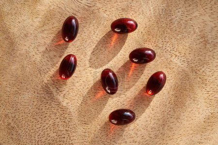 Photo for Red krill oil pills on a wooden background - Royalty Free Image