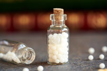 Foto de Un frasco de pastillas homeopáticas o glóbulos sobre una mesa - Imagen libre de derechos
