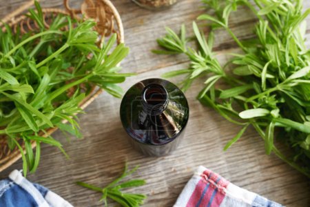 Une bouteille sombre de teinture à base de plantes avec des cliveurs frais ou une plante d'herbe à poux
