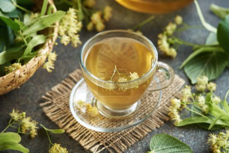 Photo for Linden flower tea in a glass cup with fresh Tilia cordata blossoms and leaves - Royalty Free Image