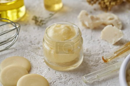 Photo for Homemade cosmetic cream with cocoa butter, essential oils and shea butter in the background - Royalty Free Image