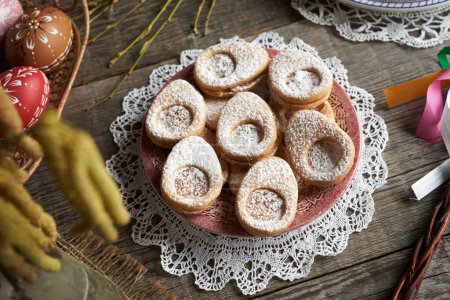 Homemade Linzer cookies in the shape of eggs with Easter decoration on a table