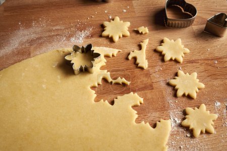 Photo for Cutting out star shapes from rolled out dough to prepare Linzer Christmas cookies - Royalty Free Image