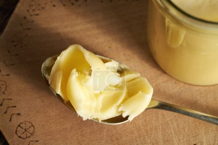 Ghee ou beurre clarifié sur une cuillère et dans un bocal en verre