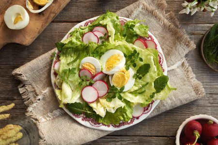 Un plato de ensalada de primavera con huevos, verduras y plantas comestibles silvestres - pollito, pezón y milenrama, vista superior