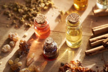 Foto de Frascos de aceites esenciales de aromaterapia con incienso y resina de mirra, canela y hierbas secas - Imagen libre de derechos