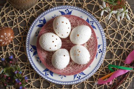 Huevo de Pascua blanco decorado con cera con flores de primavera - gotas de nieve y lombriz