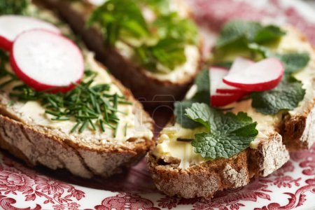 Spring wild edible plants - onion grass, garlic mustard and ground elder, on slices of sourdough bread
