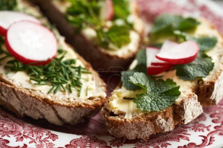 Slices of sourdough bread with wild edible plants - garlic mustard, onion grass and ground elder, close up