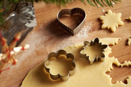 Photo for Cutting out flower and star shapes from rolled out dough to prepare traditional Linzer Christmas cookies - Royalty Free Image
