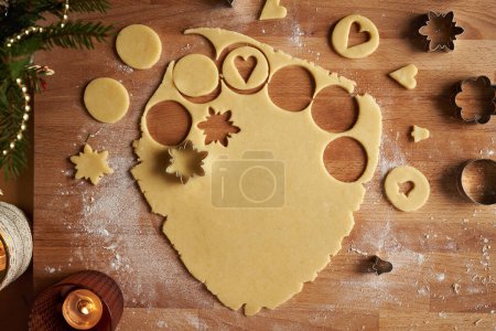 Photo for Cutting out star shapes from rolled out dough to prepare homemade Linzer Christmas cookies, top view - Royalty Free Image