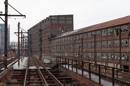 Abandoned warehouses with elevated train tracks running alongside, bleak winter Rust Belt scene, horizontal aspect